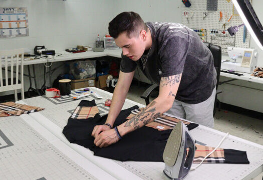 Entrepreneur works on clothing item for business.